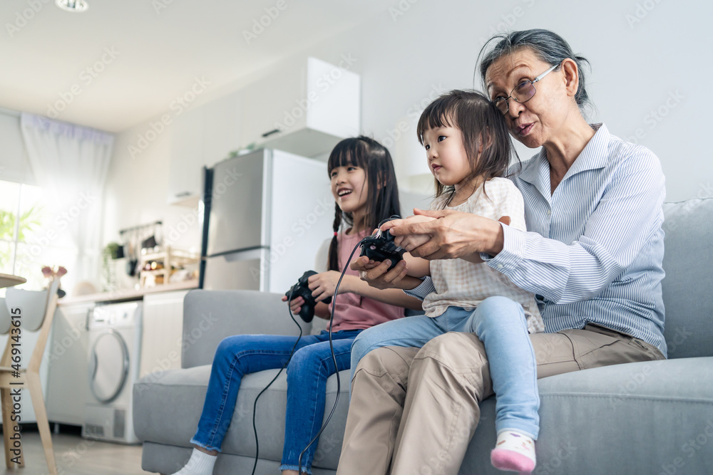 亚洲快乐家庭待在家里，奶奶和小女孩玩游戏。