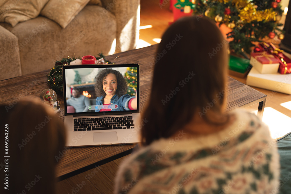 母女俩与微笑的非裔美国妇女进行笔记本电脑圣诞视频通话
