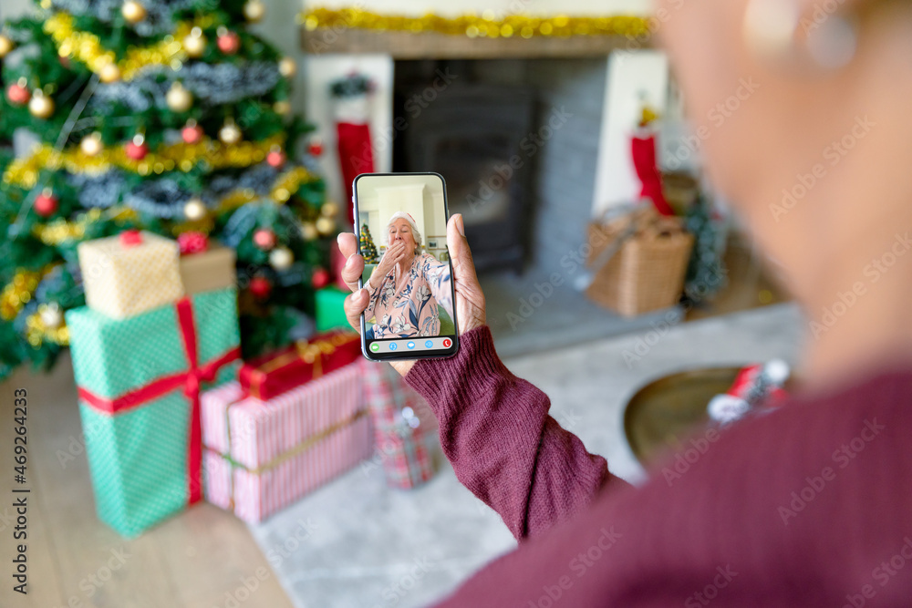 一名女子与一名快乐的白人高级女性进行圣诞智能手机视频通话