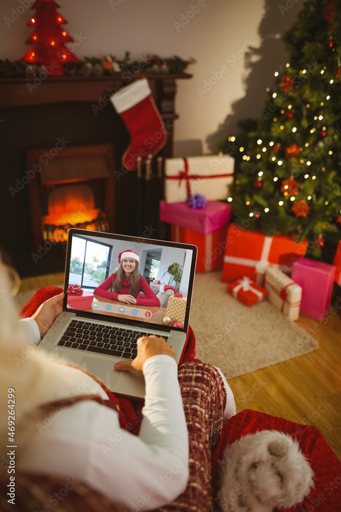 圣诞老人与戴着圣诞帽微笑的高加索妇女进行笔记本电脑圣诞视频通话