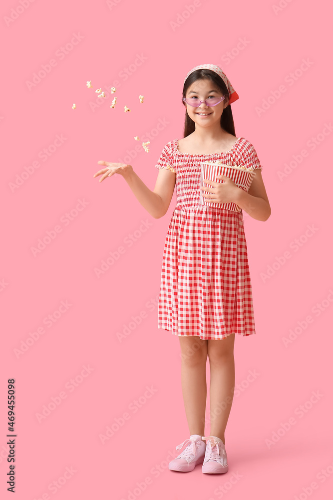 可爱的女孩在粉色背景下玩爆米花