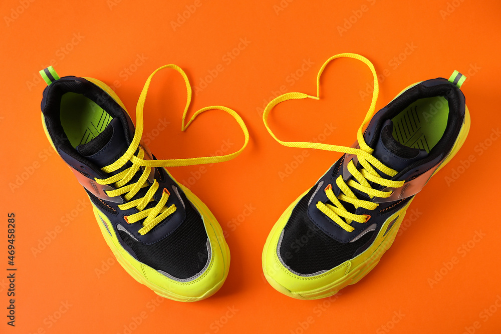 一双运动鞋和由彩色背景上的鞋带制成的心形
