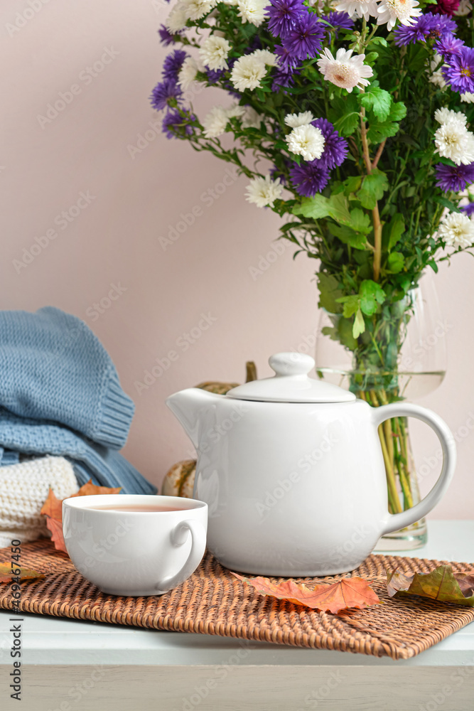 茶壶，一杯热饮，米色墙壁附近桌子上的菊花和秋叶