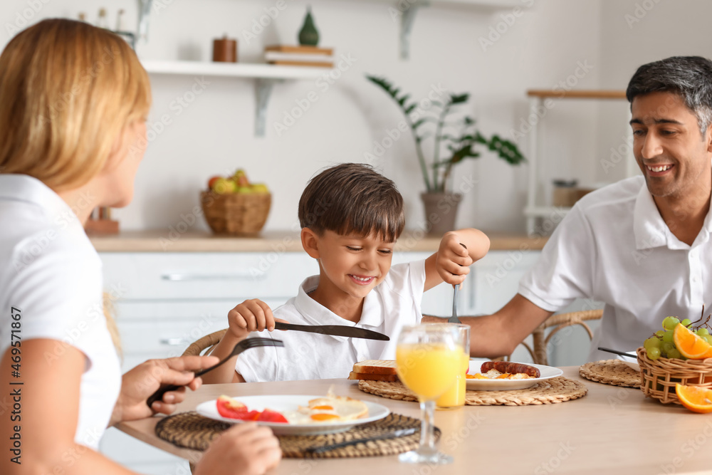 一个幸福的家庭，小儿子在厨房的桌子旁吃早餐