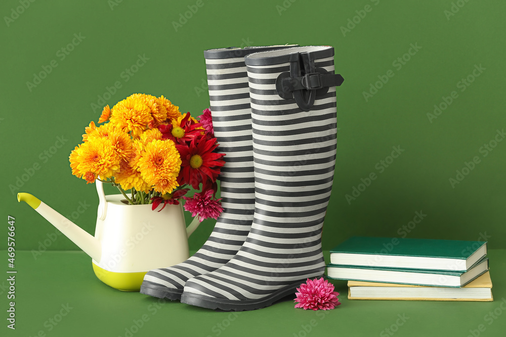 用橡胶靴、鲜花、喷壶和彩色背景书籍组成