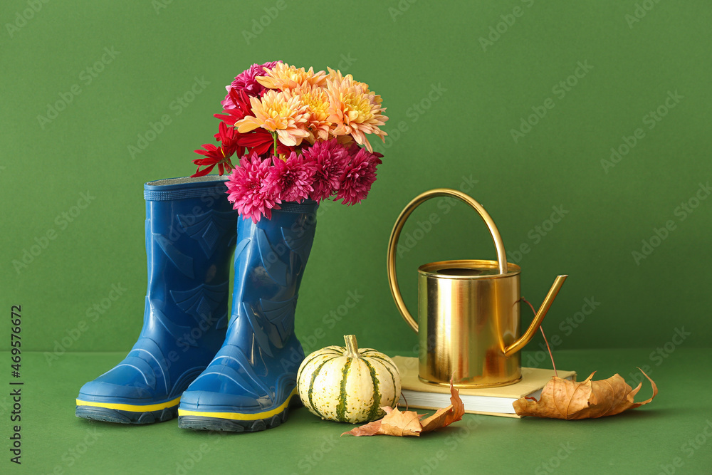 彩色背景上的橡胶靴、喷壶、书和南瓜