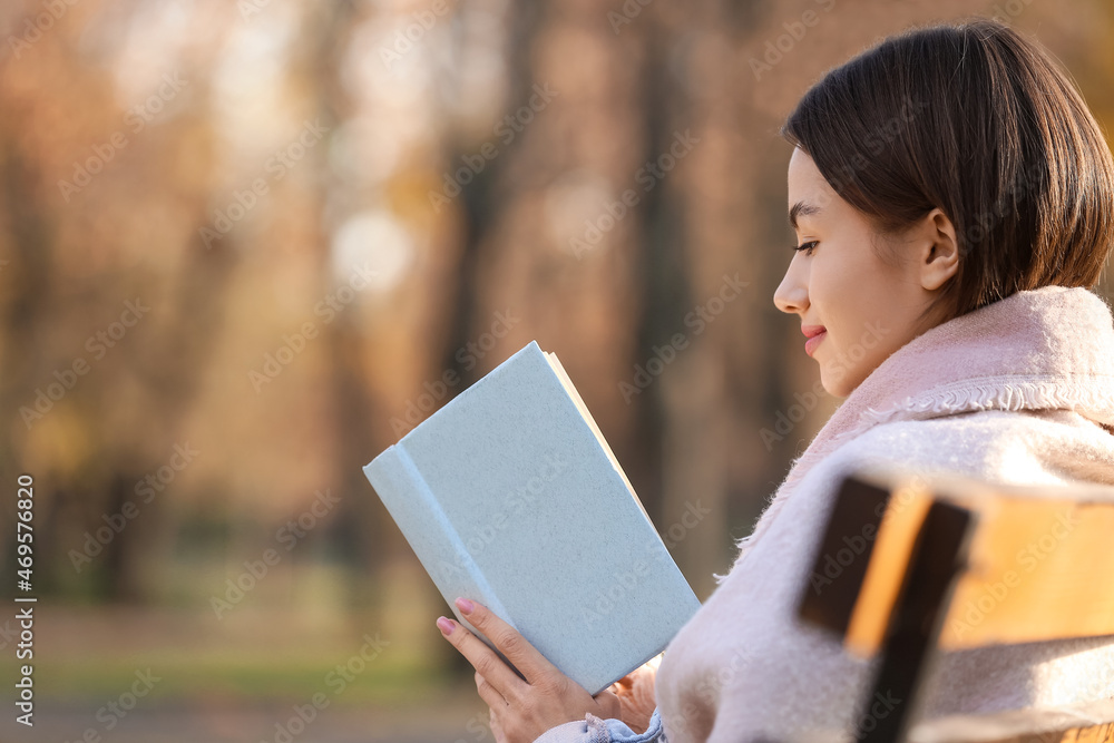 在阳光明媚的木头日子里，美丽的女人带着格子看书