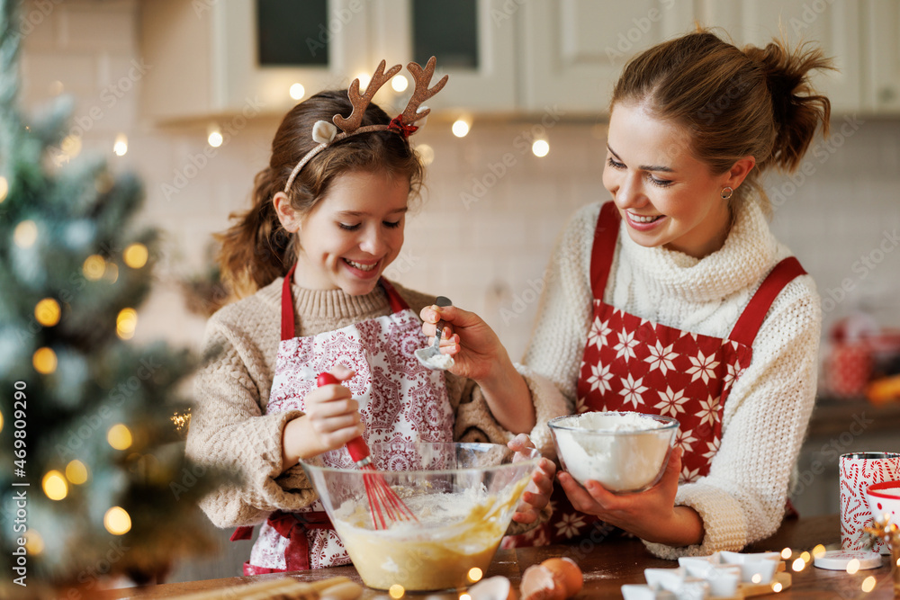 可爱的小女儿在家里舒适的厨房里帮妈妈做圣诞饼干面团