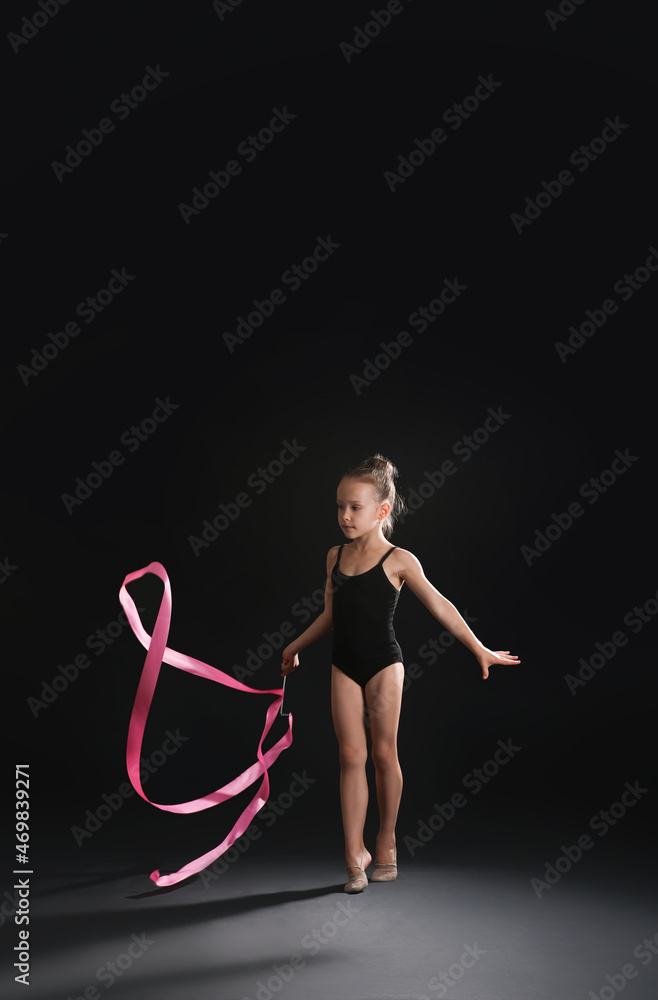 小女孩在做体操，深色背景上有缎带