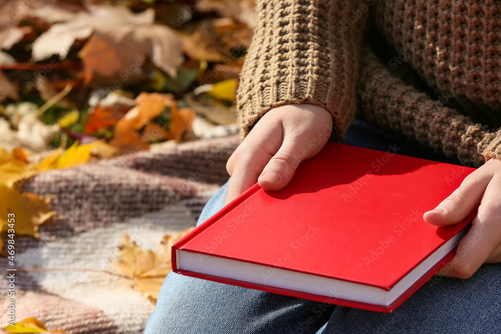 秋天公园里坐在格子布上看书的女人