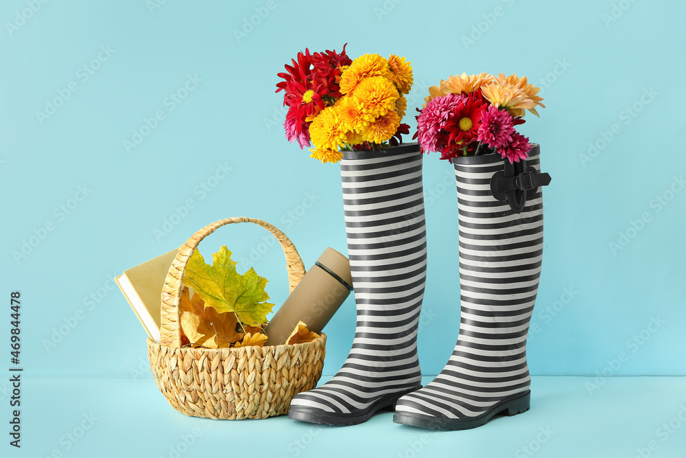橡胶靴、鲜花、篮子、保温瓶和彩色背景落叶