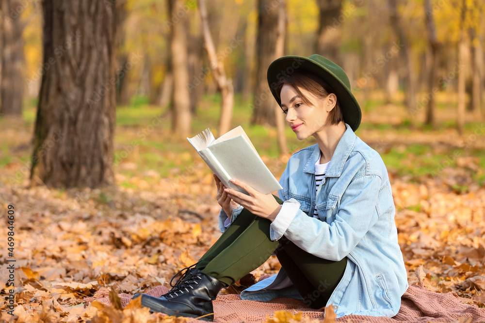 秋天公园里有一本有趣的格子书的年轻女人
