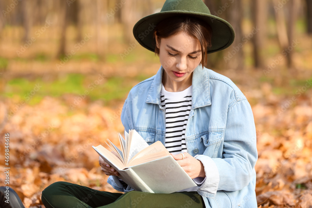 时尚女性在秋季公园看书的肖像
