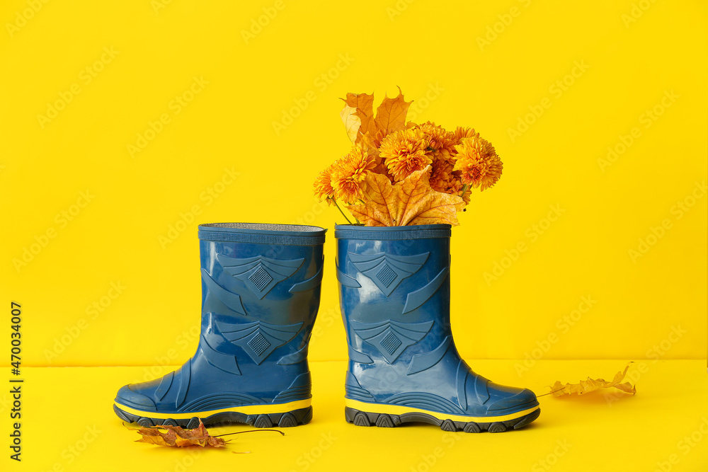 黄色背景上有花朵和落叶的橡胶靴