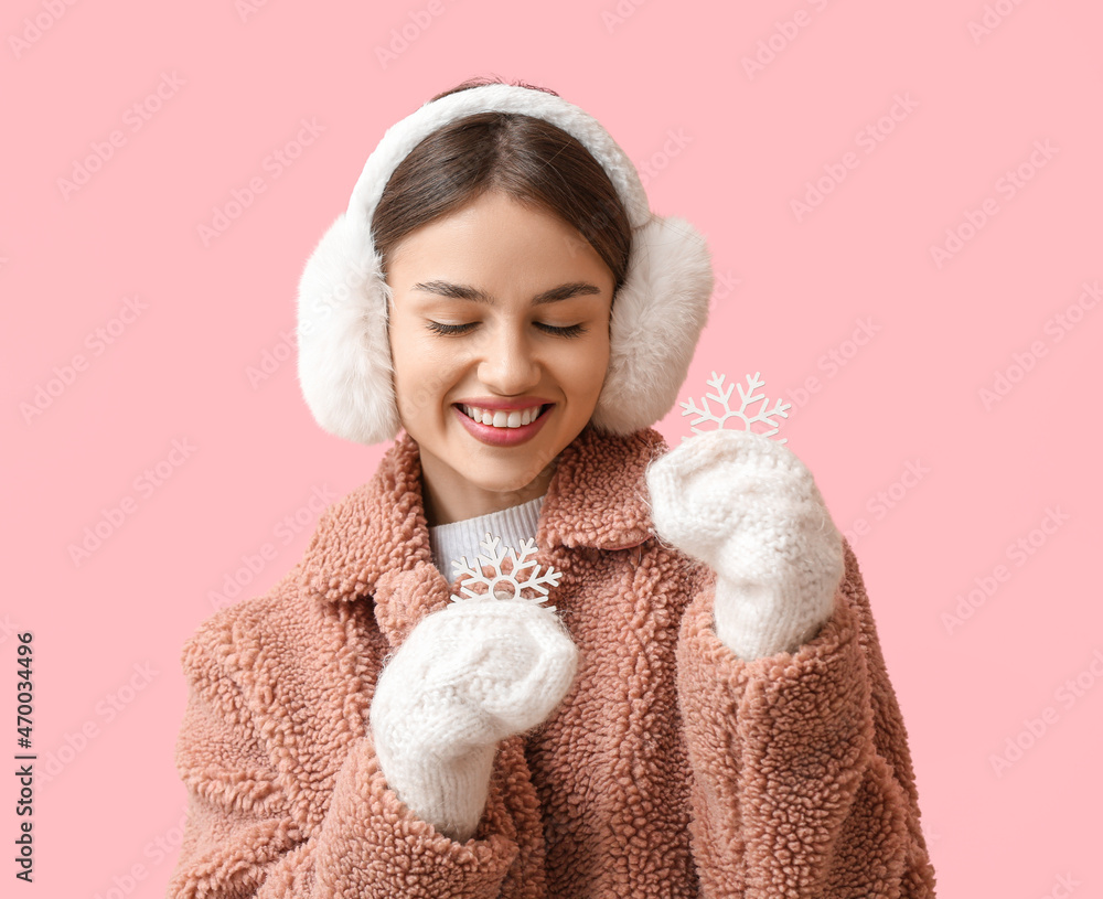 美丽的年轻女子，雪花飘飘，彩色背景上戴着蓬松的耳机