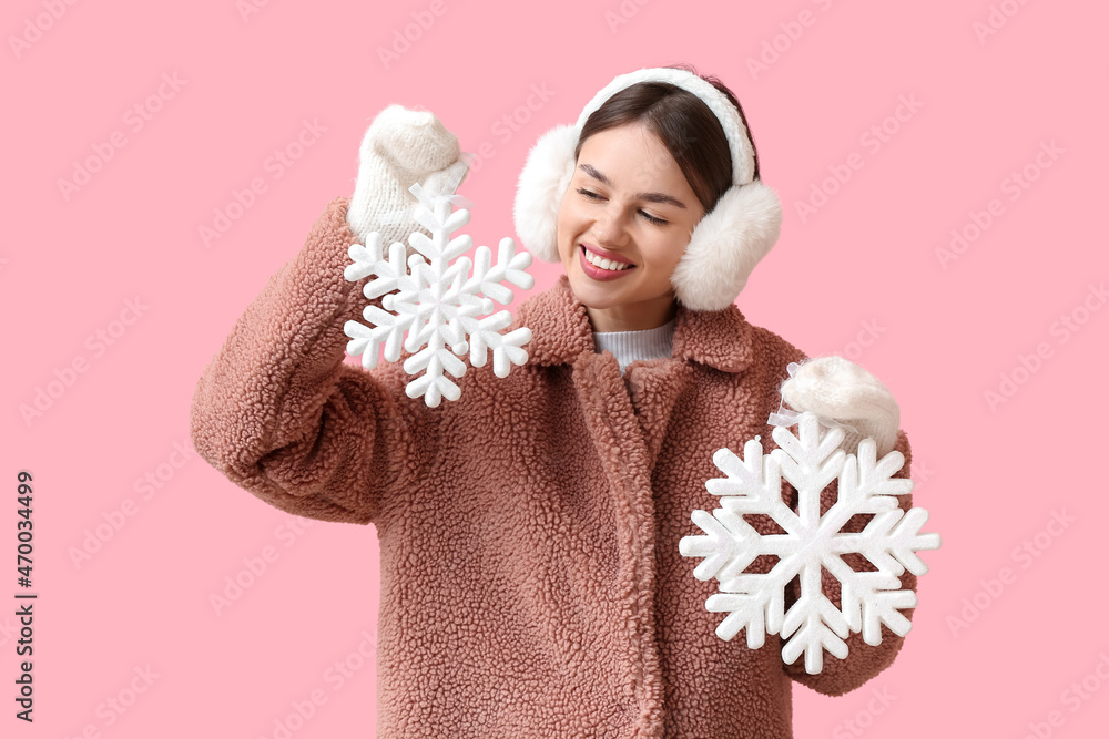 美丽的年轻女子，带着雪花，彩色背景上戴着蓬松的耳机
