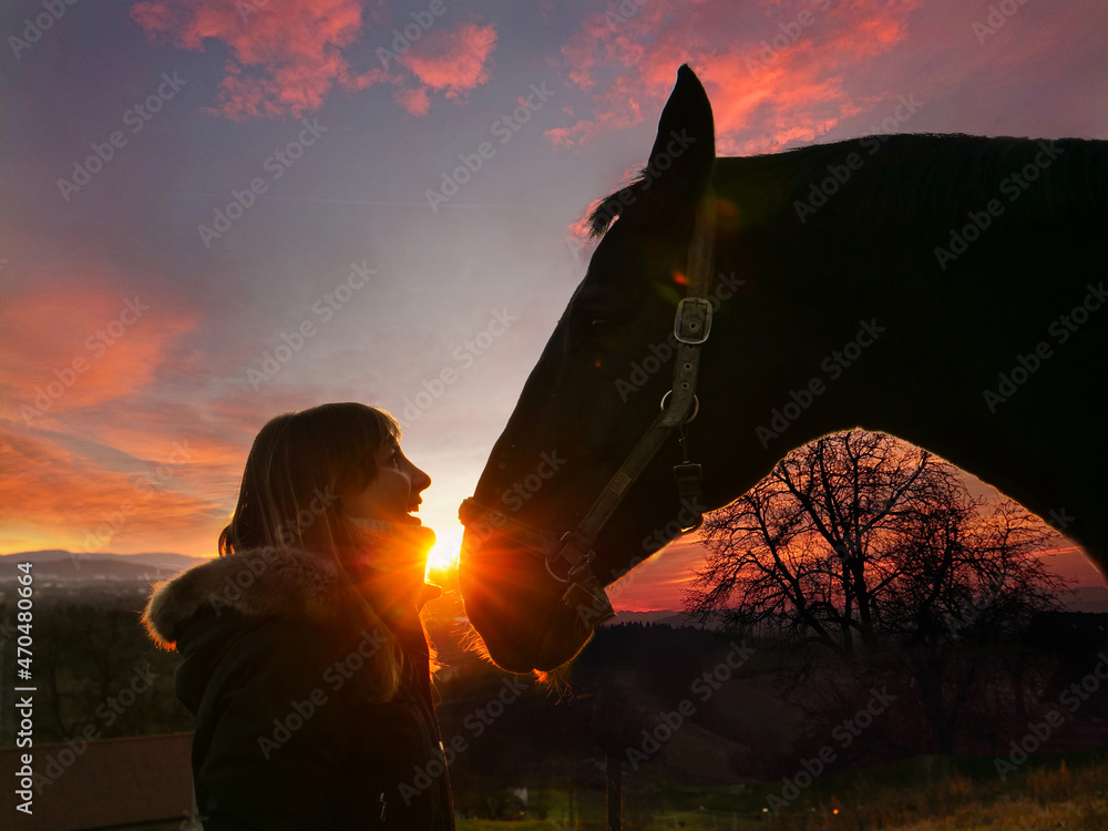 特写冬日傍晚，阳光照在女骑手身上，看着马的眼睛