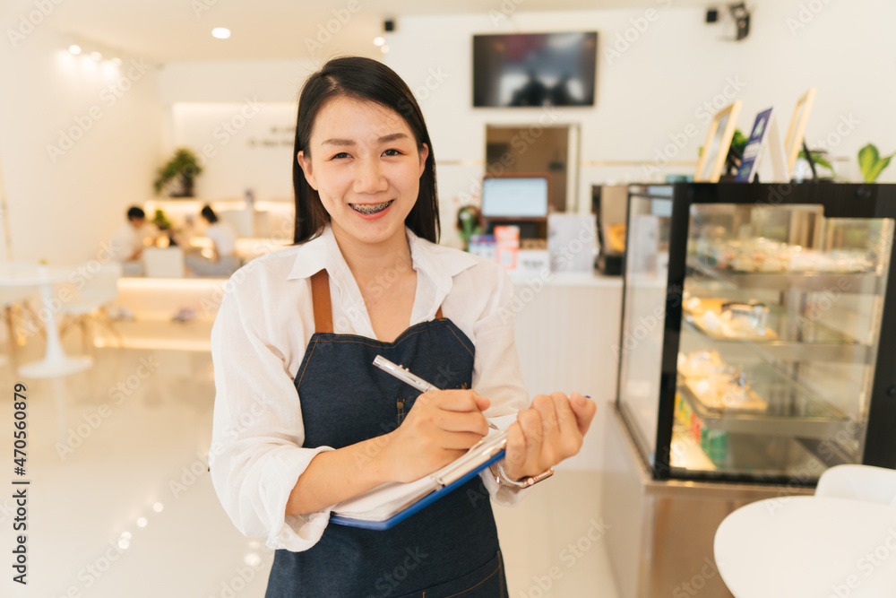 一位亚洲女士在经营一家小店时双臂交叉，站在前面微笑
