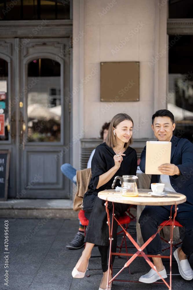 微笑的商务人士在户外咖啡馆用数字平板电脑进行视频通话。远程和f的概念