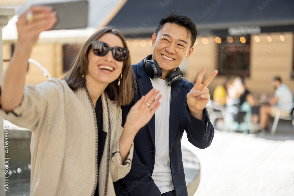 一对微笑的夫妇在城市喷泉区用智能手机自拍。城市生活的概念。想法