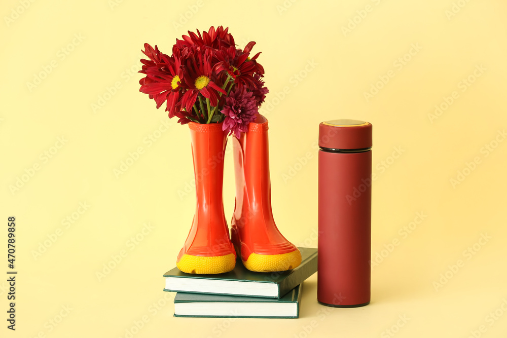 彩色背景的橡胶靴、花、保温瓶和书