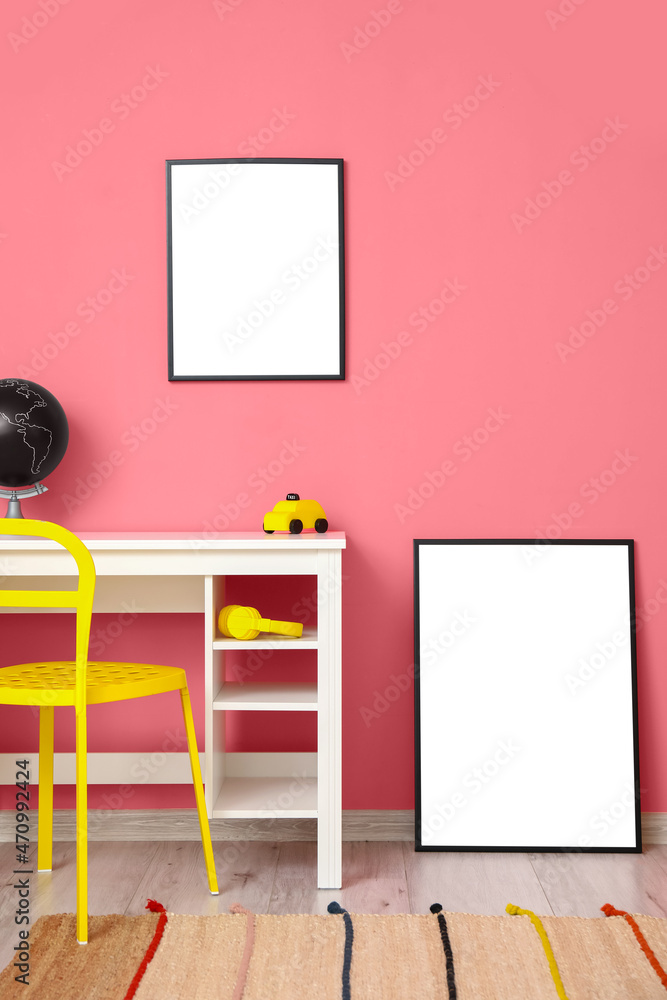 粉色墙壁附近的空白框架和白色桌子