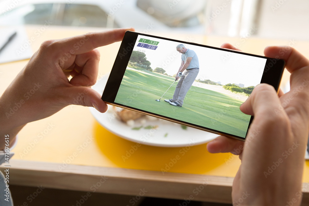 餐厅里用智能手机观看高尔夫比赛的白人男子的手