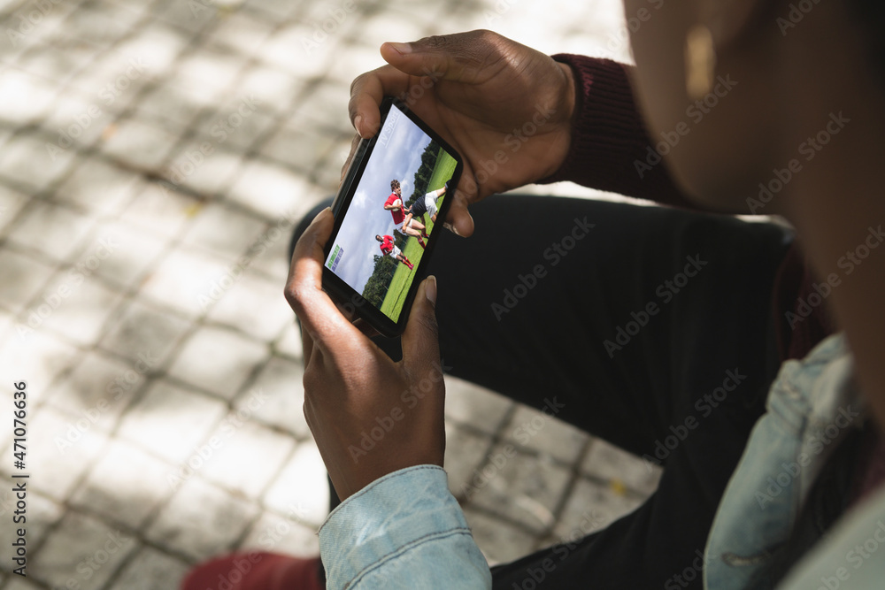 公园里的非裔美国人用智能手机观看橄榄球比赛