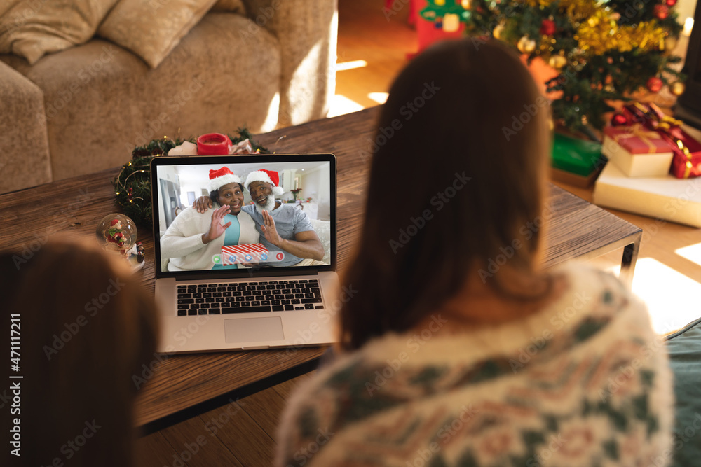 母女与幸福的非洲裔美国老年夫妇进行笔记本电脑圣诞视频通话