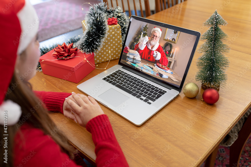 戴圣诞老人帽的白人妇女与穿着圣诞老人服装的老年男子进行笔记本电脑圣诞视频通话