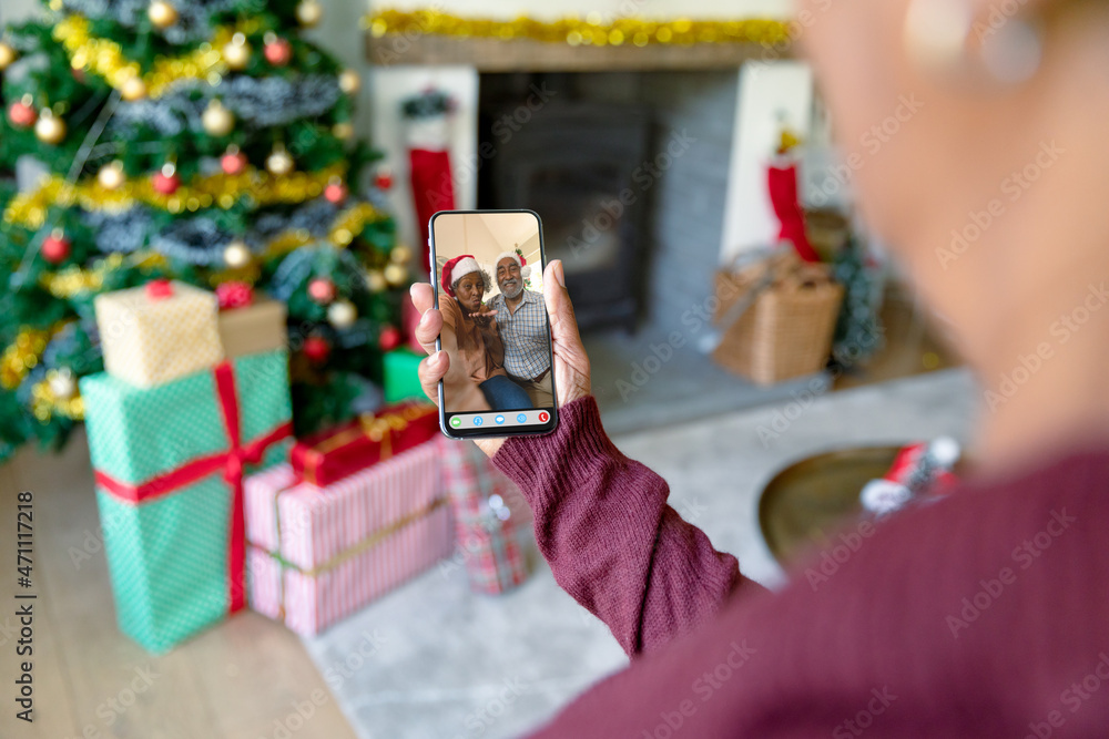 一位女士与一对微笑的非洲裔美国老年夫妇进行智能手机圣诞视频通话