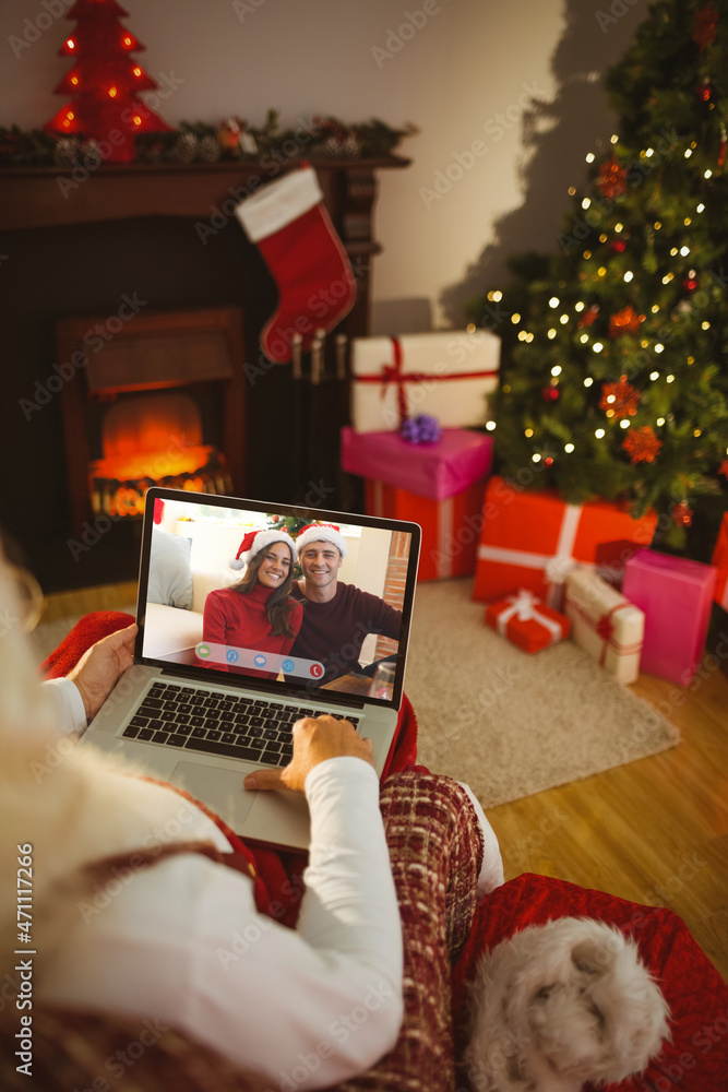 圣诞老人与戴着圣诞老人帽微笑的高加索夫妇进行笔记本电脑圣诞视频通话