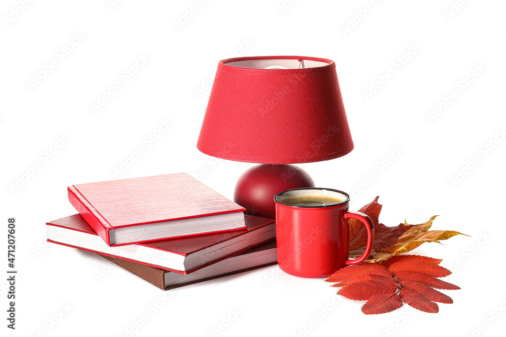 白色背景下的一叠书、一盏灯、一杯咖啡和秋叶