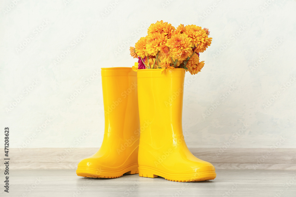 一双黄色橡胶靴和淡墙菊花