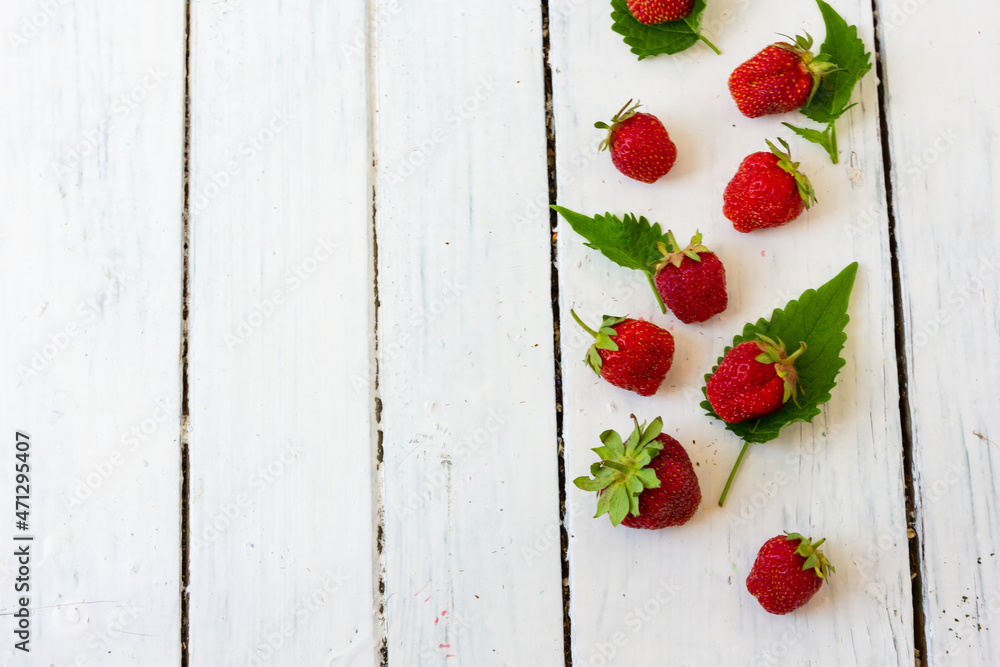 成熟的红草莓呈木白色背景上的框架状。复制空间。查看正面