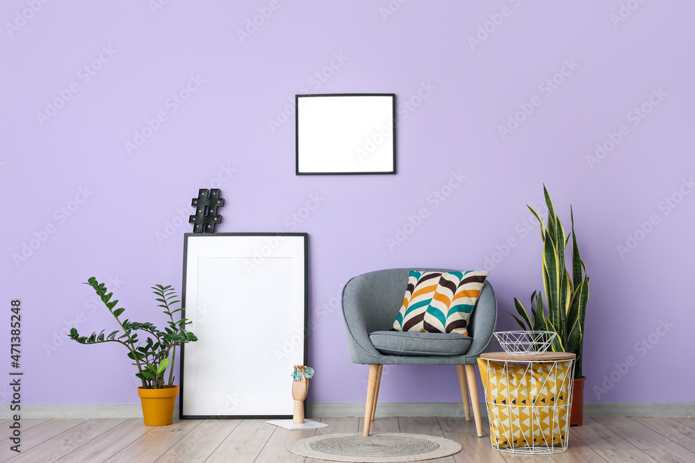 淡紫色墙壁附近的灰色扶手椅的空白框架
