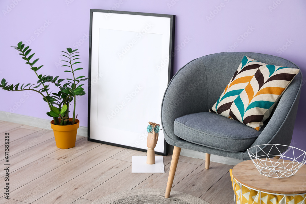 淡紫色墙壁附近的带室内植物和灰色扶手椅的空白框架