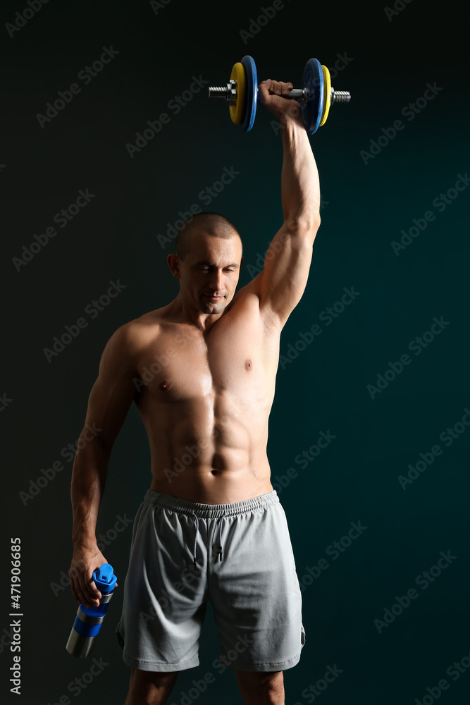 男性健美运动员，深色背景下有蛋白奶昔和哑铃