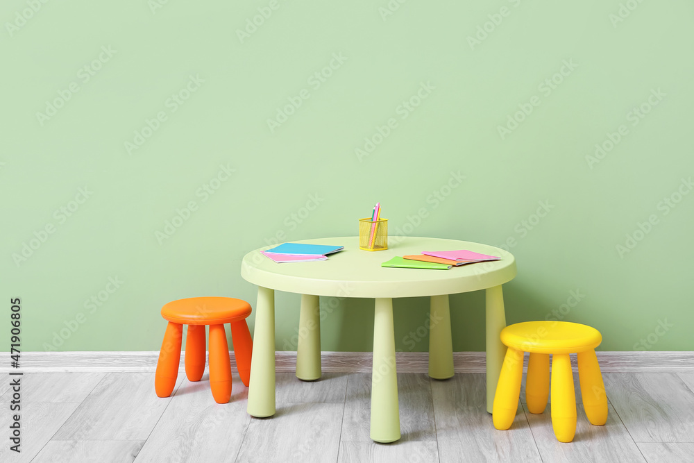 儿童房彩色墙附近的桌子和文具