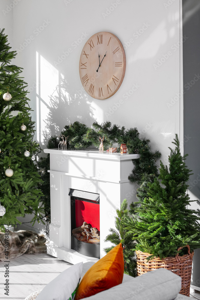 壁炉、装饰圣诞树和浅色墙上的木制时钟