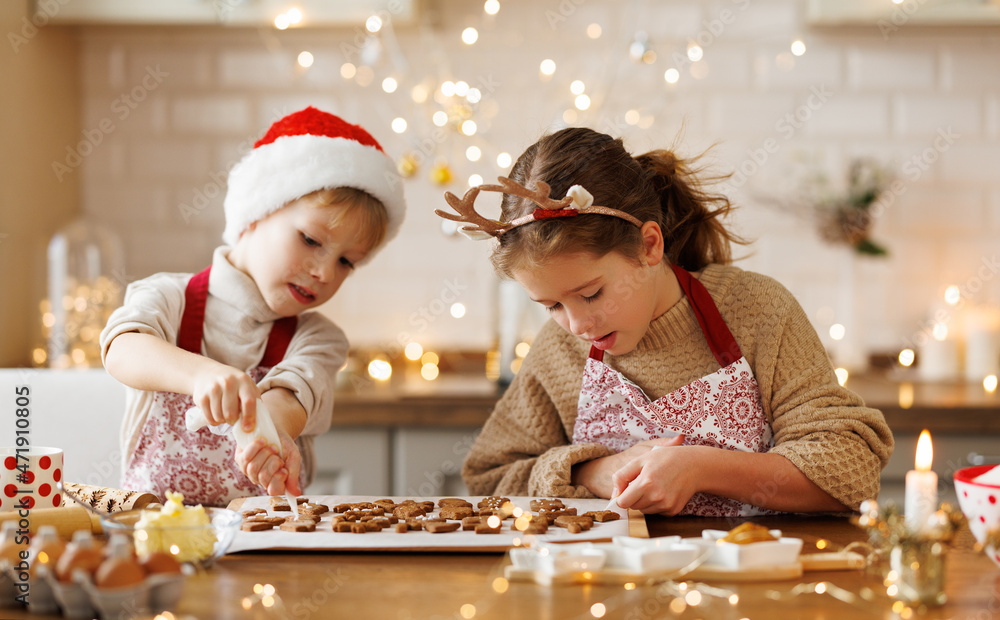 快乐的孩子男孩和女孩在厨房装饰圣诞姜饼时微笑