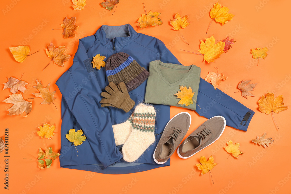 男夹克、帽子、手套、毛衣、袜子、鞋子和彩色背景秋叶