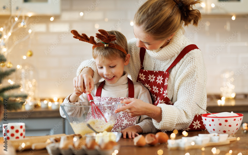 可爱的小男孩在家里舒适的厨房里帮妈妈做圣诞饼干面团