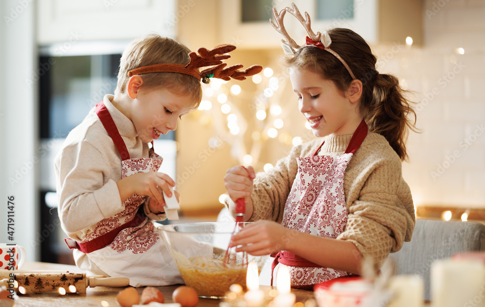 Happy children boy and girl smiling  while decorating Christmas gingerbreads in kitchen