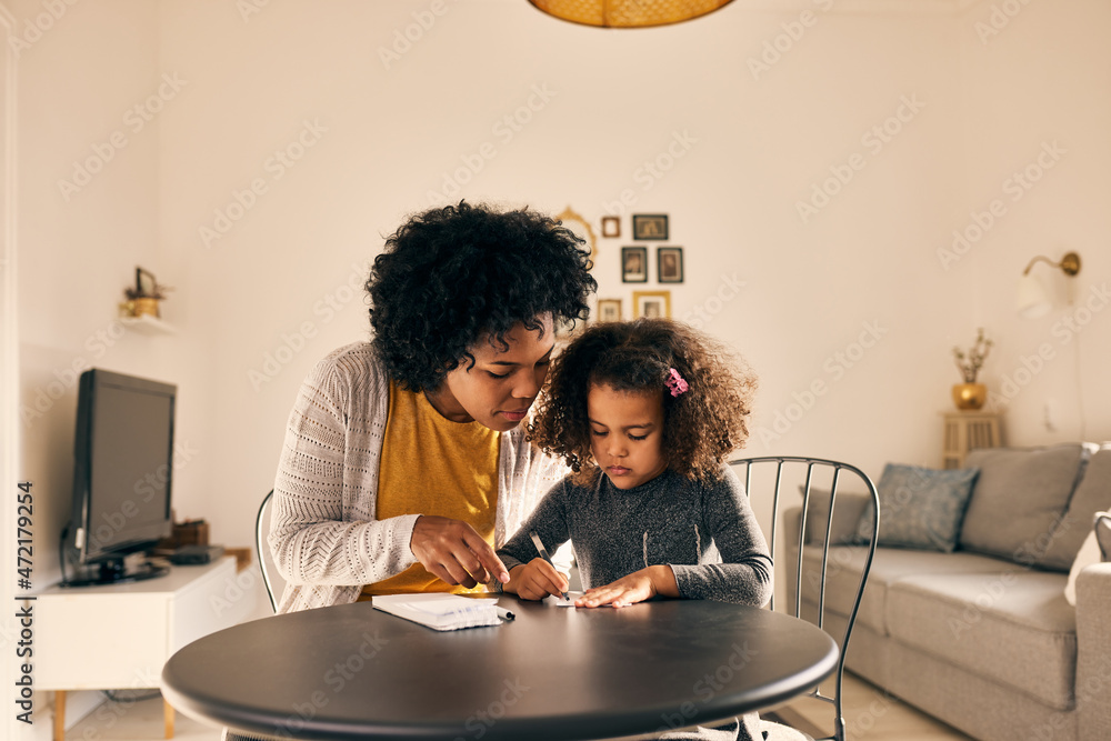 Serious adult woman, helping her child to study