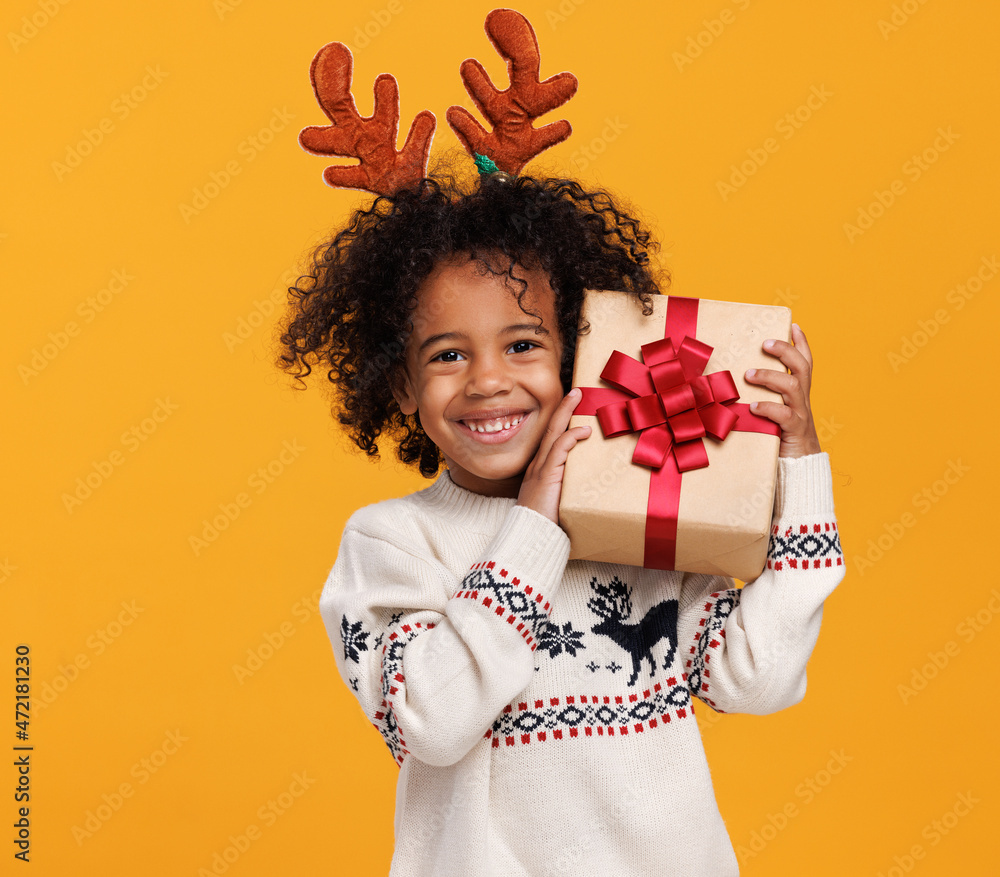 圣诞假期。快乐的非洲裔美国小男孩戴着红色鹿角和圣诞礼物盒