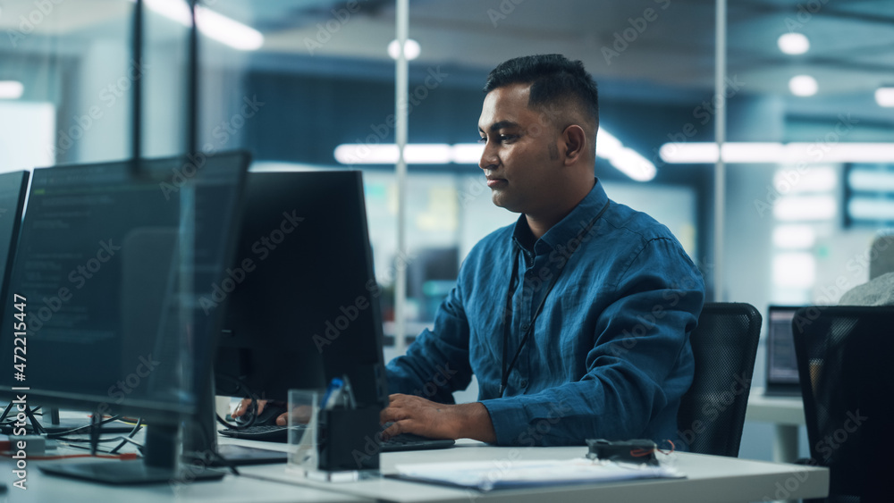 在多样化的办公室：在台式电脑上工作的英俊印度男人的肖像。专注于专业