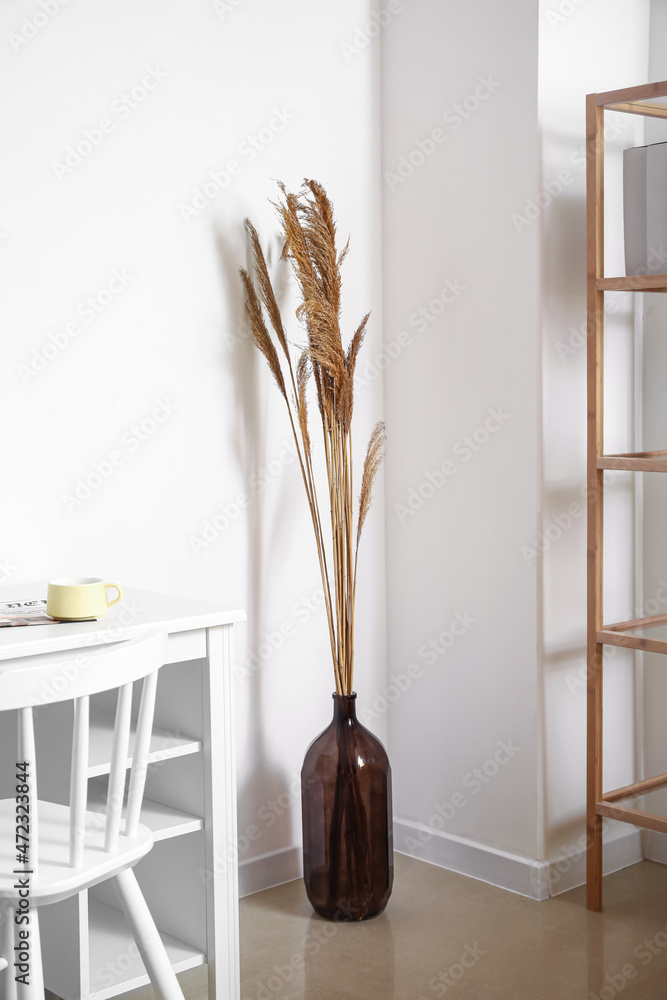 浅色墙壁附近桌子上的干芦苇花瓶