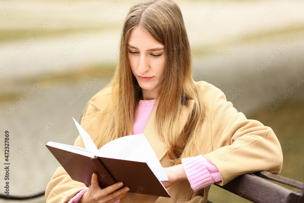 秋天公园长椅上的女人在读有趣的书