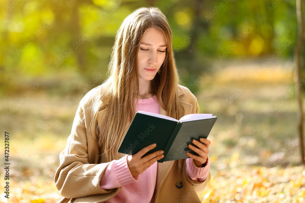 阳光明媚的一天，年轻女子在秋季公园看书
